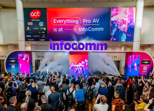 Large crowd gathered at the illuminated InfoComm trade show entrance with fog effects and LED signage.