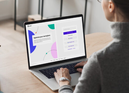 Woman typing on a laptop displaying the Joan workplace management platform sign-in page.