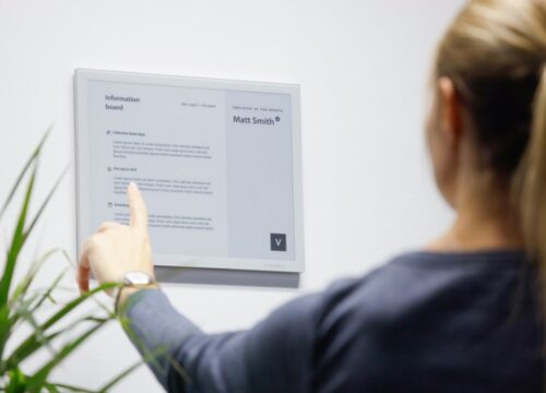 Employee reading an internal announcement on a Joan workplace display.