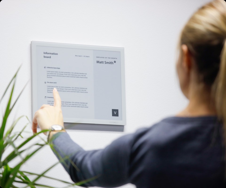 Employee reading an internal announcement on a Joan workplace display.