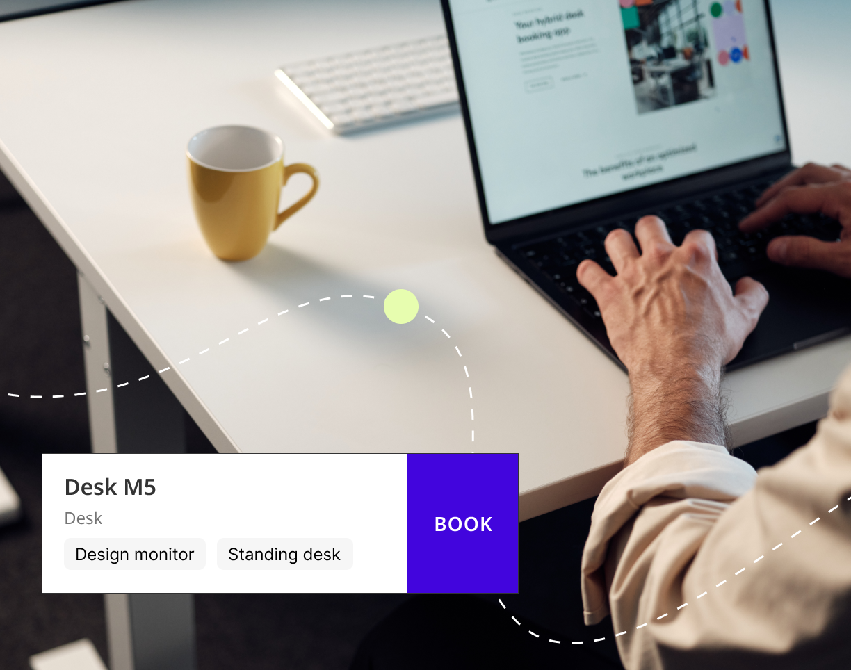 Person at desk with laptop and a desk booking interface card showing Desk M5 with a Book button.