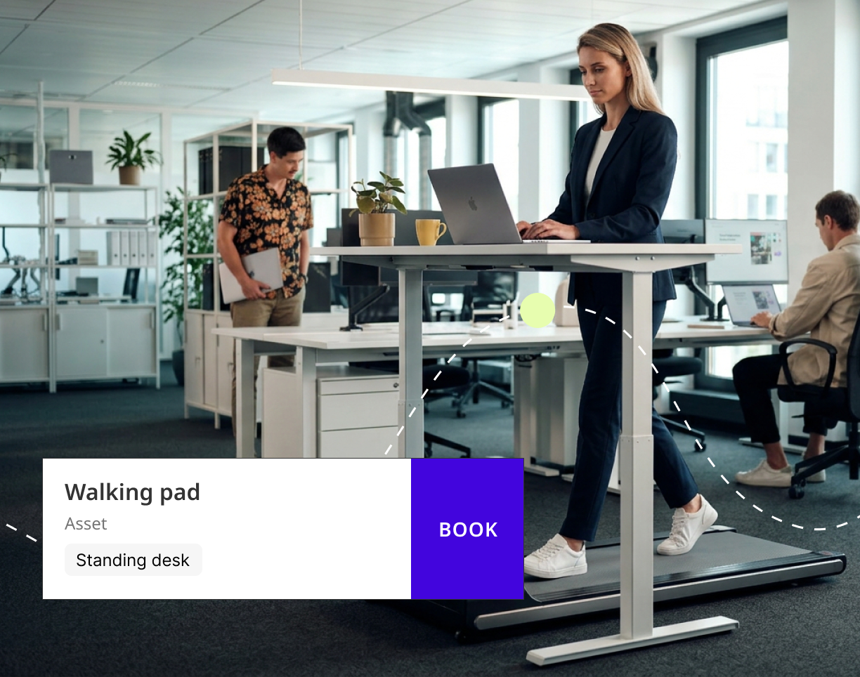 Woman using laptop on standing desk with walking pad, showing a booking overlay for office assets.