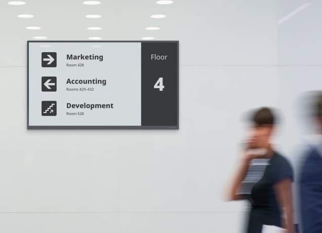Wall-mounted office wayfinding sign on Floor 4 directing visitors to Marketing, Accounting, and Development departments.