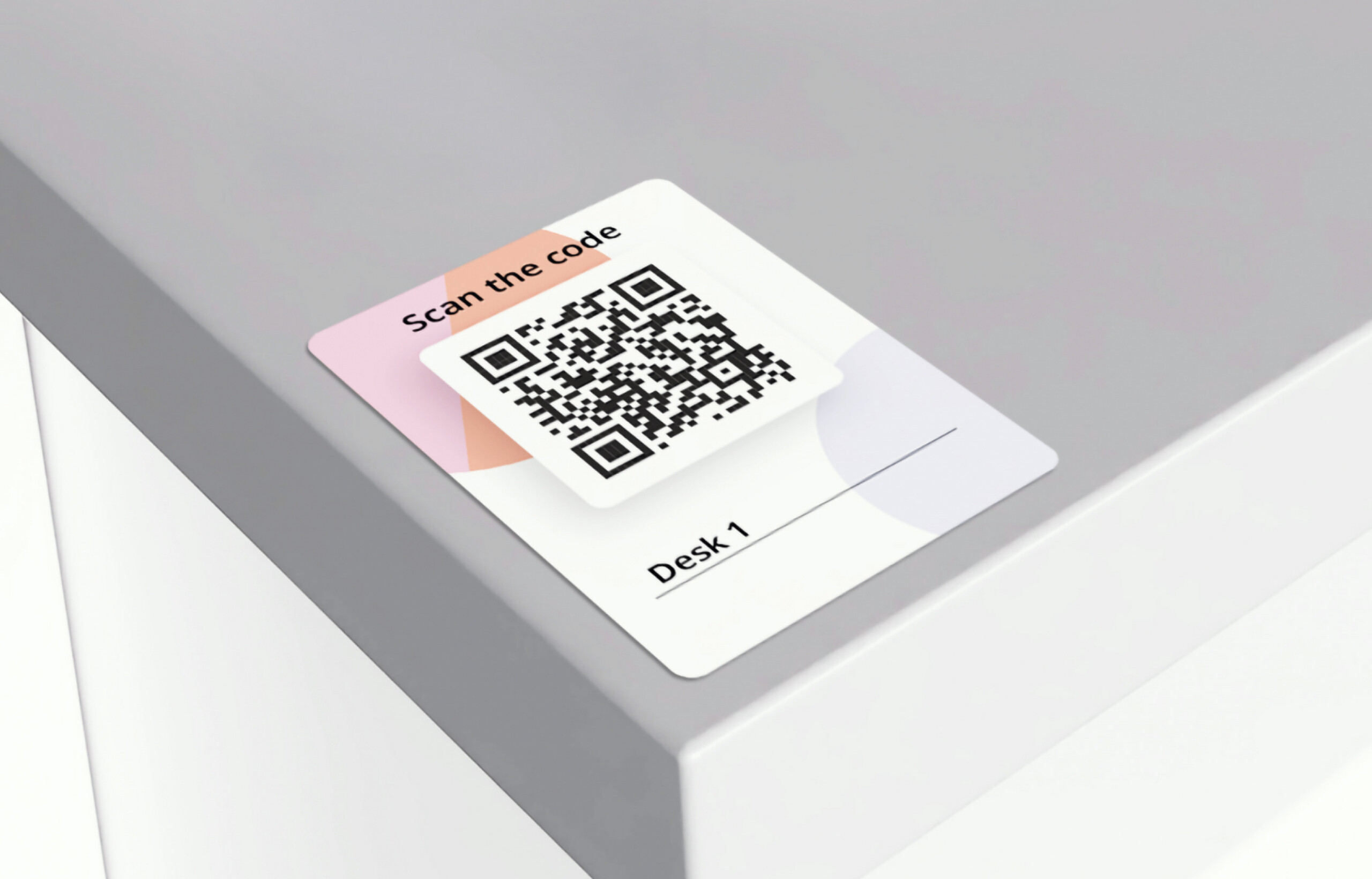 QR code desk booking card labeled 'Desk 1' placed on a gray office desk surface.